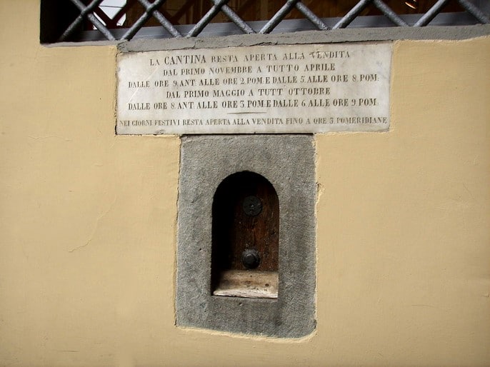 Fen&ecirc;tre &agrave; vin de la Via del Sole &agrave; Florence surmont&eacute;e d'une plaque indiquant le r&egrave;glement de vente de vin
